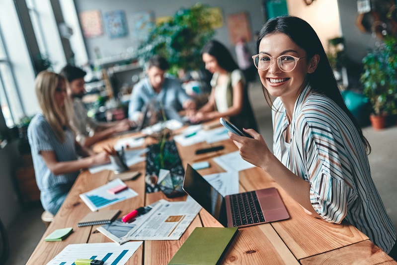 Educators sitting around a long table work-shopping, with an educator facing the camera and smiling