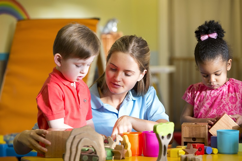 Educator supporting children to play with blocks