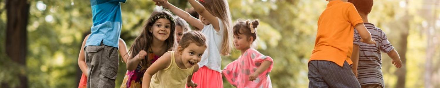 Two children making a bridge with their arms with other children running through underneath the arch 