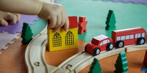 Child playing with a wooden train set on the floor