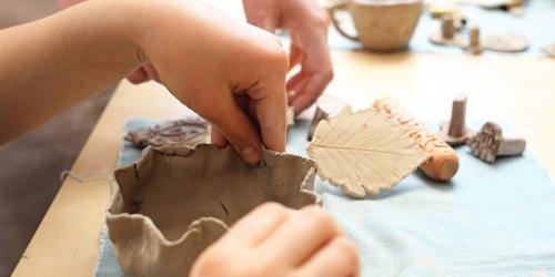 Child's hands creating a clay pinch pot
