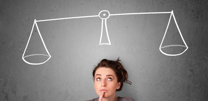 Educator looking up at the ceiling with a chalk drawing of a set of balanced scales on the blackboard behind them