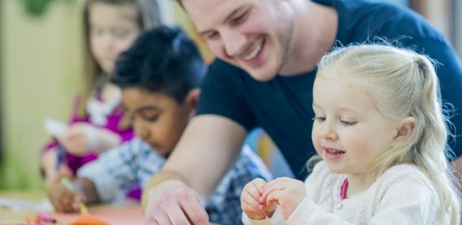 Educator assisting children with organising crayons for a drawing activity