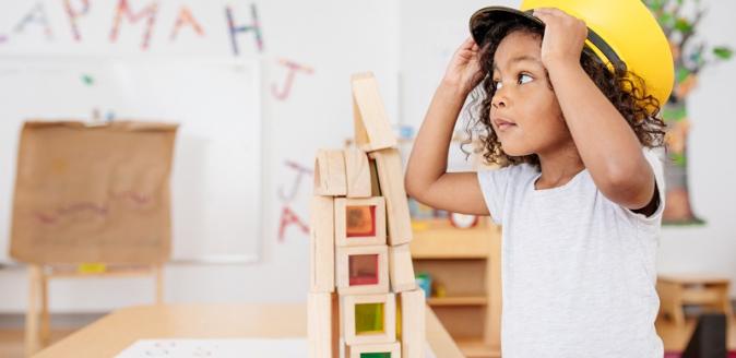 Young child trying on a conductor hat in an education setting