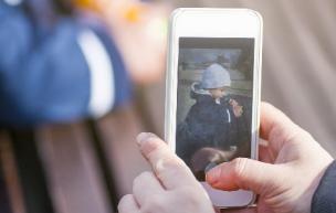 Person holding a mobile phone and taking a picture of a child sitting at a table