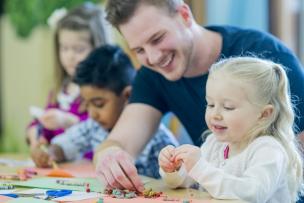 Educator assisting children with organising crayons for a drawing activity