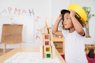 Young child trying on a conductor hat in an education setting