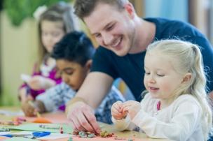 Educator and child sitting at a table and enjoying working on a craft activity together