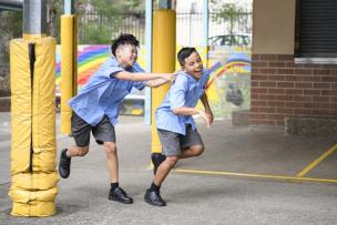 Two school aged children running and laughing in a school yard